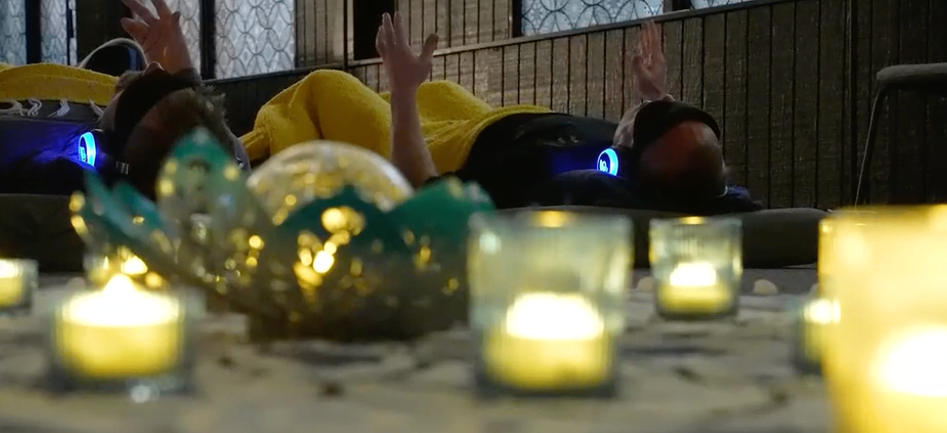 Hands raised during breathwork with candles in the foreground