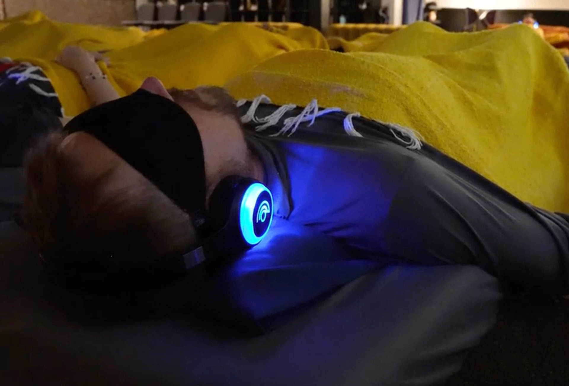 Guest resting with glowing headphones during 9D breathwork